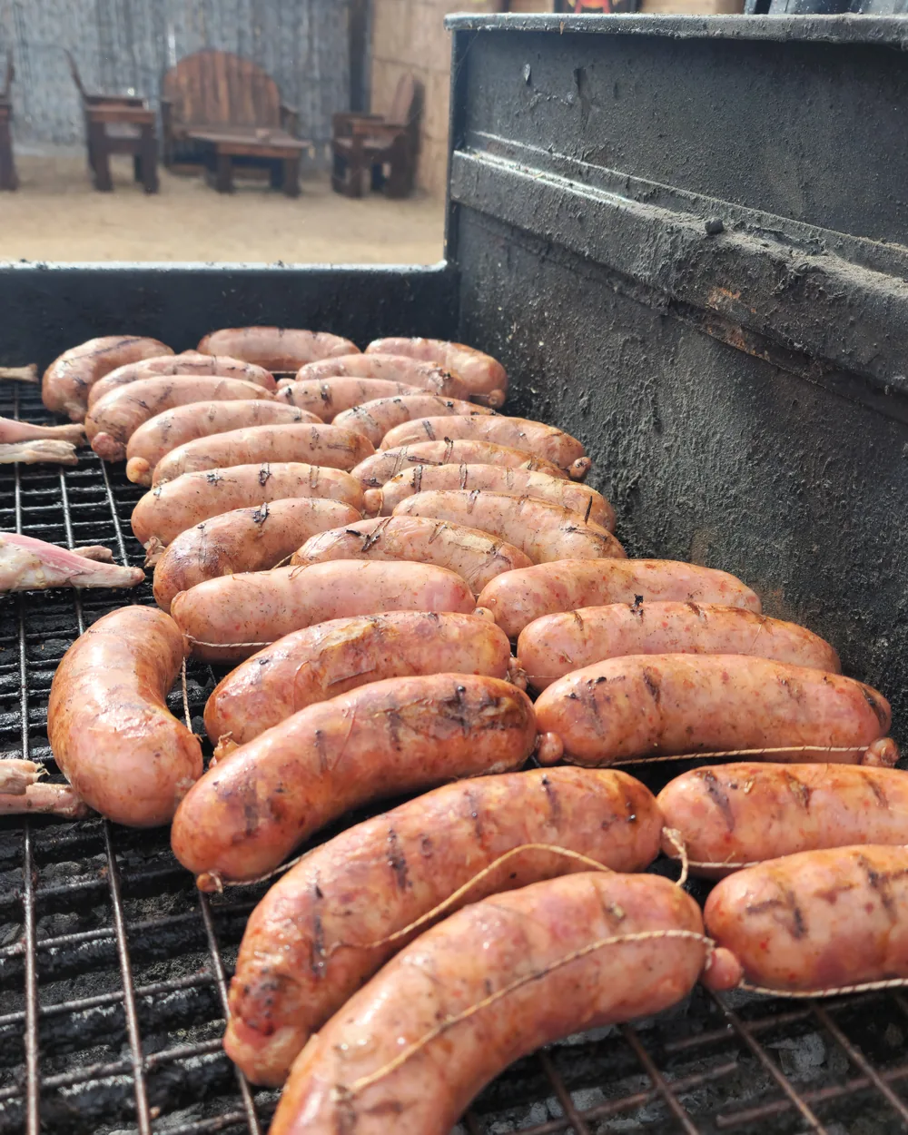 Chorizos atados en fila sobre la parrilla, todavía crudos